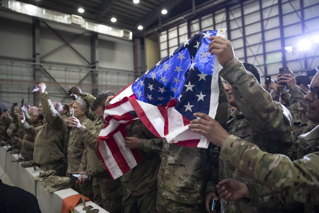 Miembros del ejército despliegan una bandera estadounidense mientras el presidente Donald Trum ...