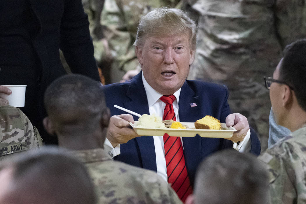 El presidente Donald Trump sostiene una bandeja de la cena de Acción de Gracias durante una vi ...