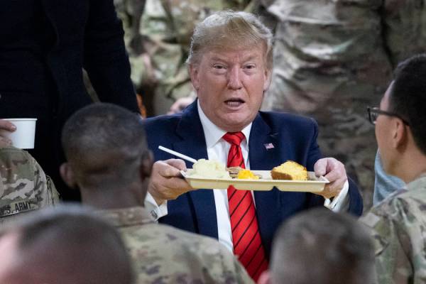 El presidente Donald Trump sostiene una bandeja de la cena de Acción de Gracias durante una vi ...