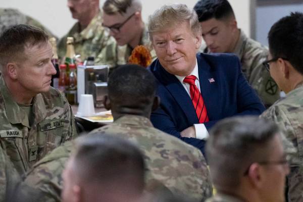 El presidente Donald Trump sonríe mientras está sentado con las tropas durante una visita sor ...