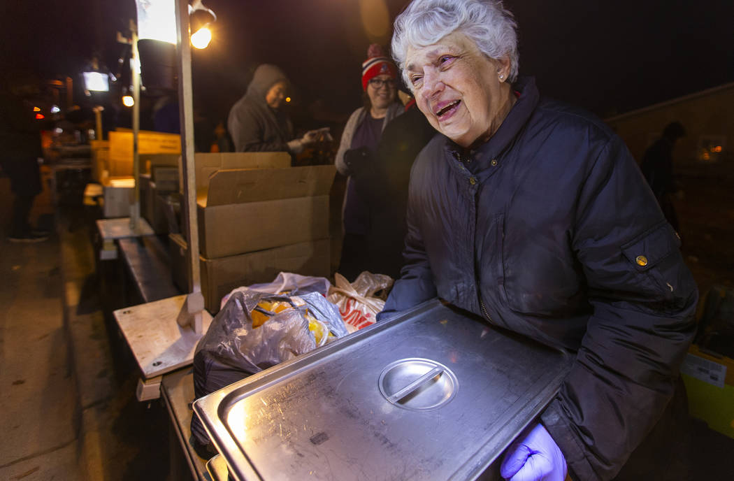 La voluntaria Christine Ruland ayuda a servir una cena caliente a los necesitados reunidos para ...