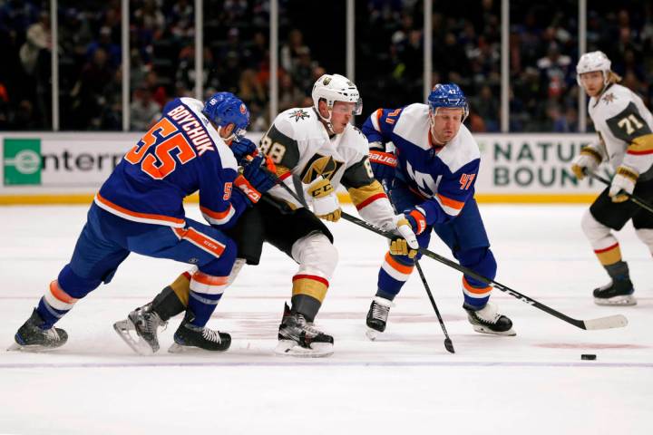 El defensa de los Islanders, Johnny Boychuk (55), y el ala derecha, Leo Komarov (47), rodean al ...