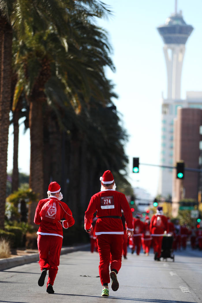 La gente corre en el 14º Great Santa Run anual de Las Vegas en el centro de Las Vegas el sába ...