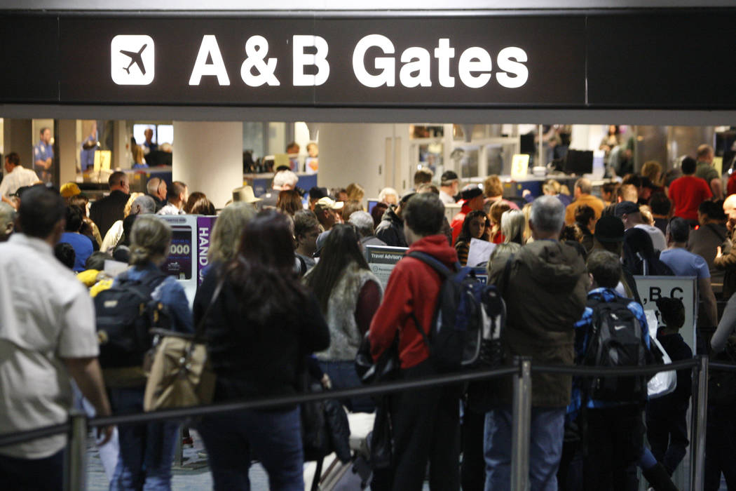 Pasajeros esperan en fila para pasar la seguridad en la Terminal 1 del Aeropuerto Internacional ...