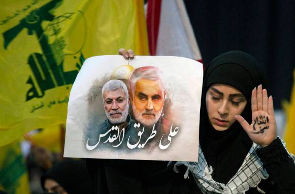 Una partidaria del líder de Hezbolá, Sayyed Hassan Nasrallah, lleva en la mano las palabras " ...