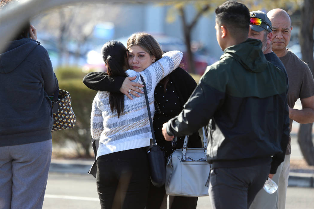 Gente se abraza después de abandonar la escena de un tiroteo en el que estuvieron involucrados ...