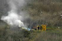 Bomberos trabajan en la escena de un accidente de helicóptero en el que murió la ex estrella ...