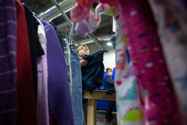 Linda Muth, arriba/izquierda, clasifica la ropa donada en Goodwill del sur de Nevada el miérco ...