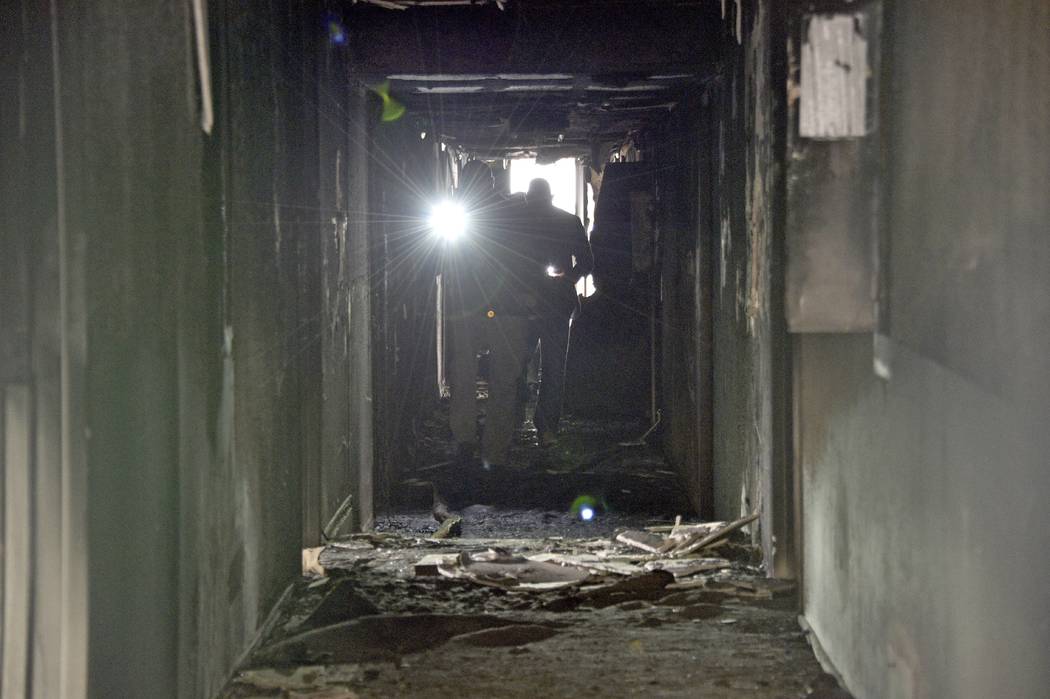 Los investigadores caminan por un pasillo interior después de un incendio en un complejo de ap ...