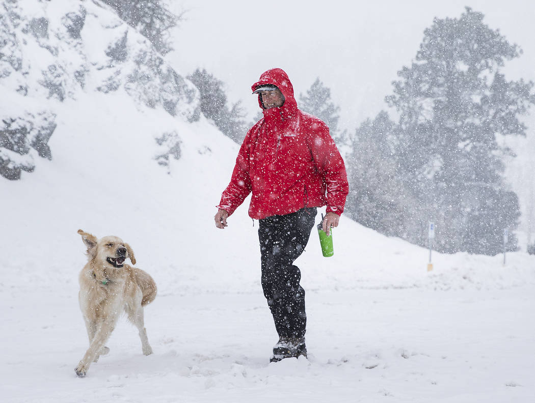 Paul Whitmoyer, a la derecha, y su golden retriever Kona caminando en la nieve en el Mount Char ...