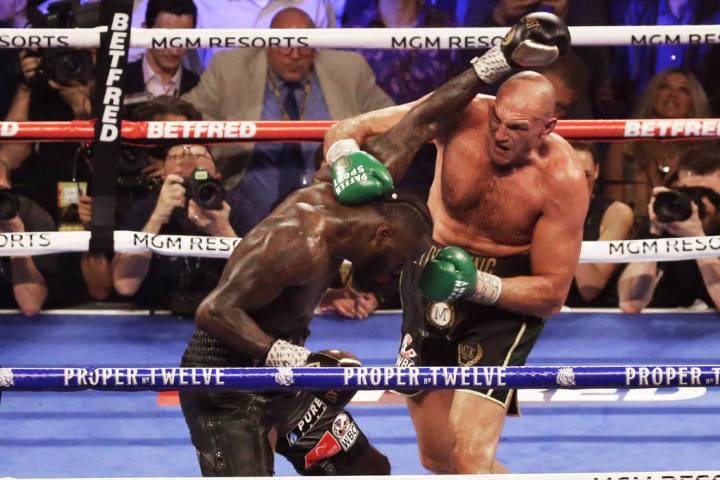 Tyson Fury, derecha, conecta con un gancho de derecha contra Deontay Wilder en el quinto asalto ...