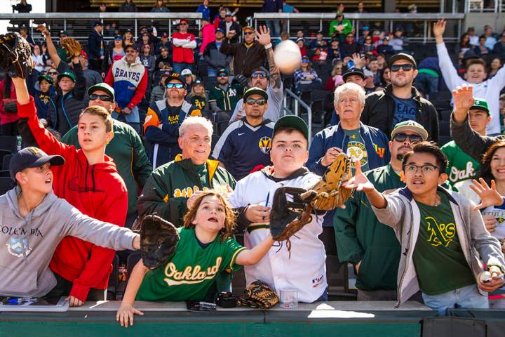 Los fans intentan atrapar una pelota lanzada por un jugador de los A's de Oakland durante un pa ...