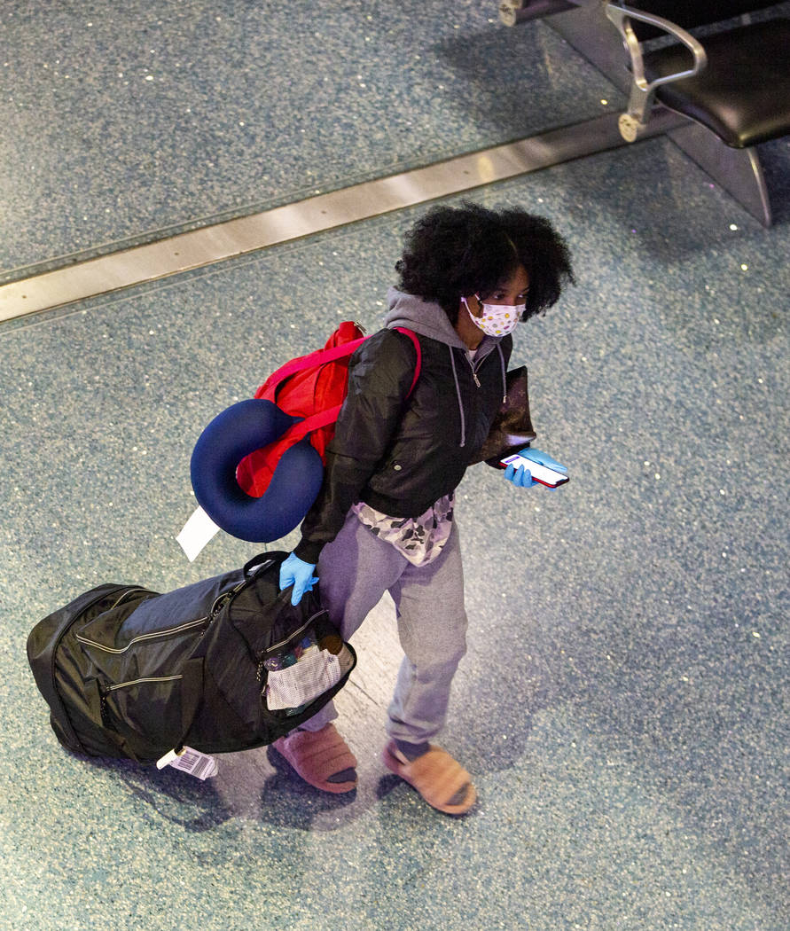 Una pasajera usa una máscara facial mientras camina por la Terminal 1 del aeropuerto internaci ...