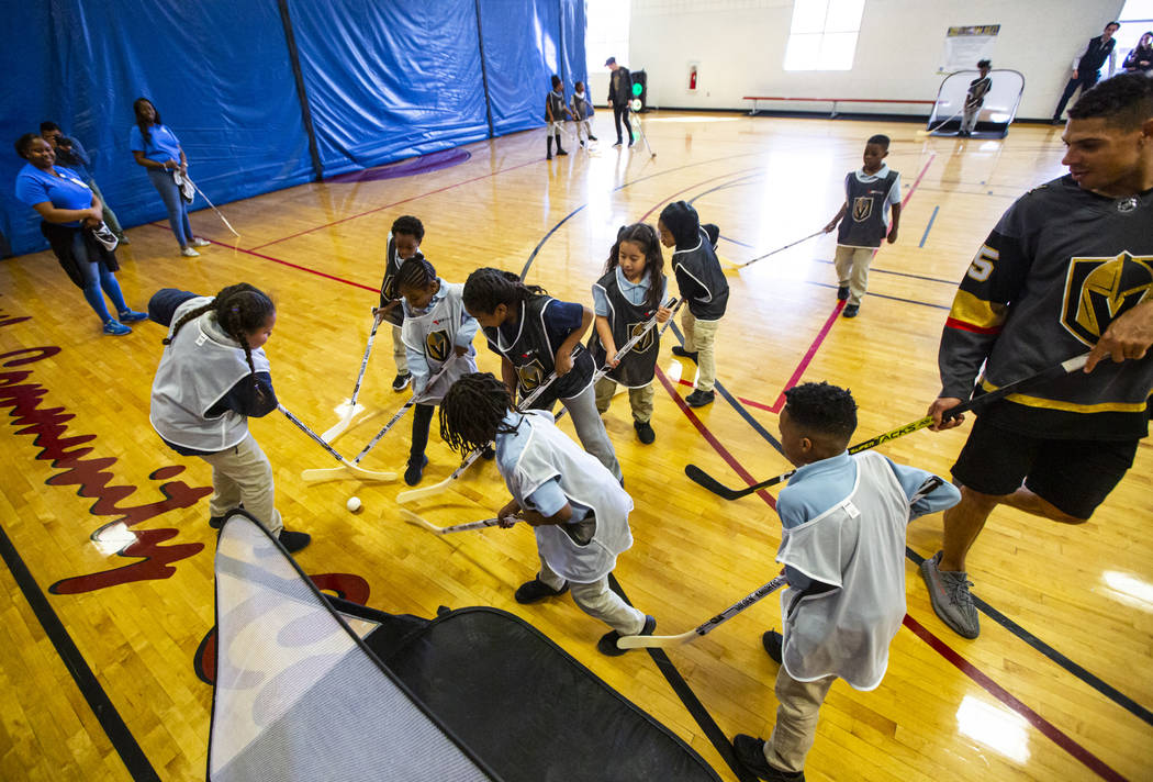 Los niños luchan por la pelota durante una clínica de hockey callejero para jóvenes en el Ce ...