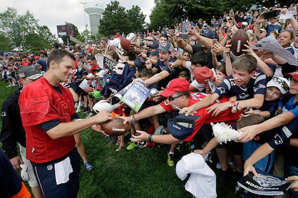 Tom Brady, de los Patriots de Nueva Inglaterra, izquierda, firma autógrafos para los aficionad ...