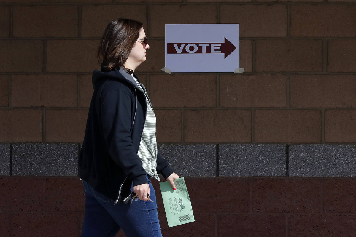 Una votante de Arizona entrega su boleta de voto por correo en un centro de votación para la e ...