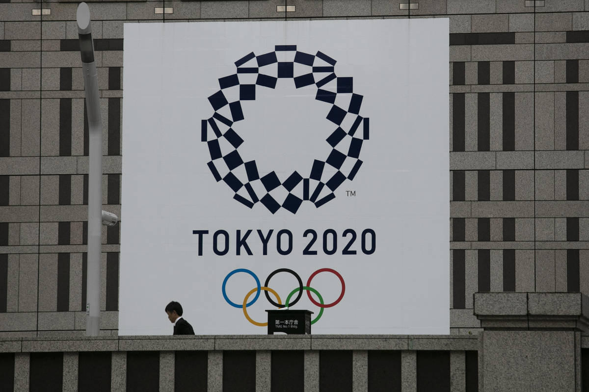 Un hombre pasa junto a una gran pancarta promocionando las Olimpiadas de Tokio 2020 en Tokio el ...