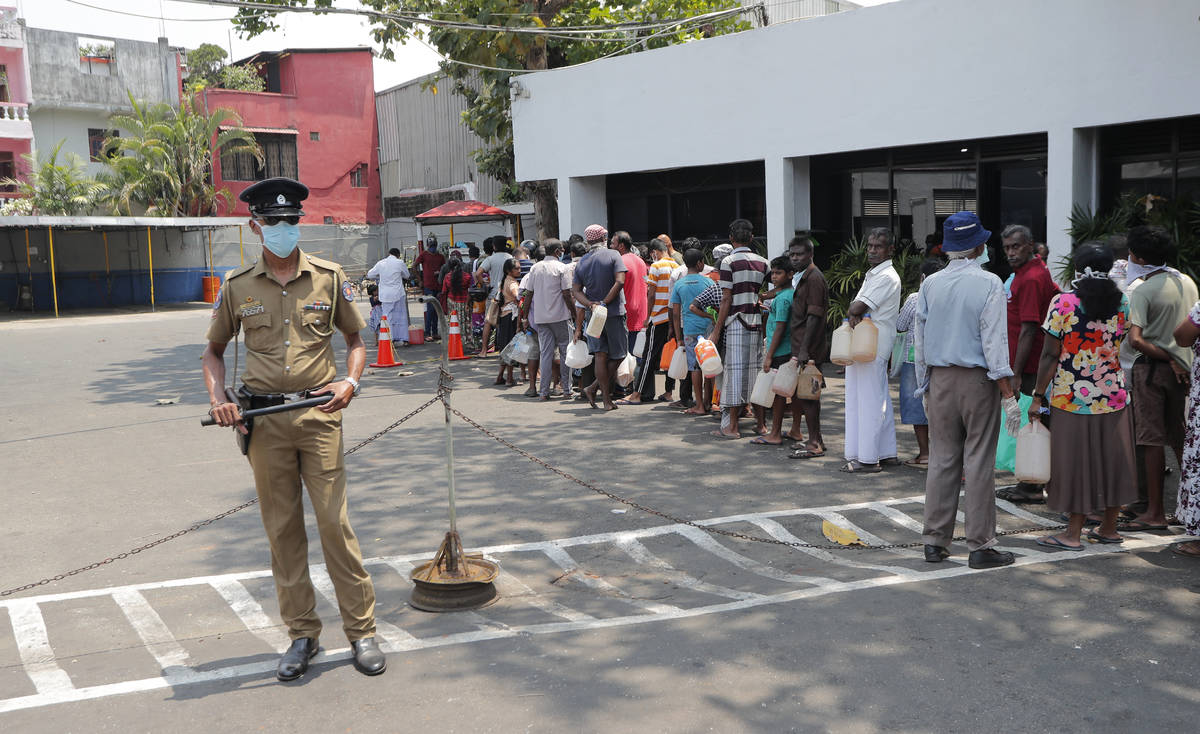 Los habitantes de Sri Lanka hacen fila para obtener queroseno mientras un agente de policía ha ...