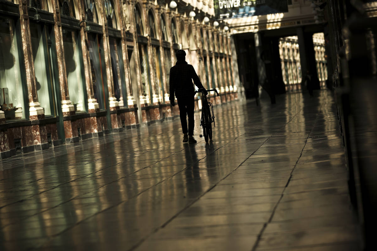 Un hombre camina a lo largo de una calle comercial prácticamente vacía de la Galería Real de ...