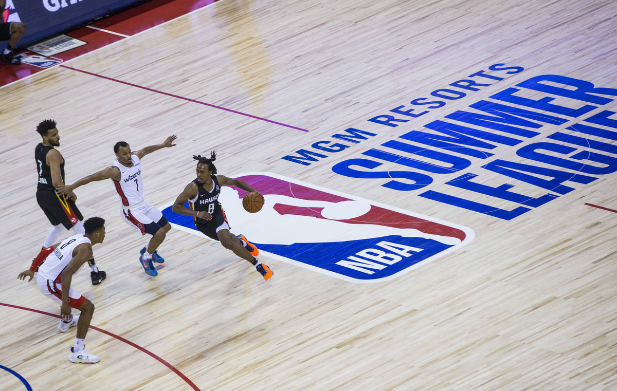 Tahjre McCall (8) de los Atlanta Hawks, lleva el balón a la cancha pasando a Justin Robinson ( ...