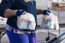 Un trabajador reparte paquetes de desayuno y almuerzo a las familias en una escuela en marzo de ...