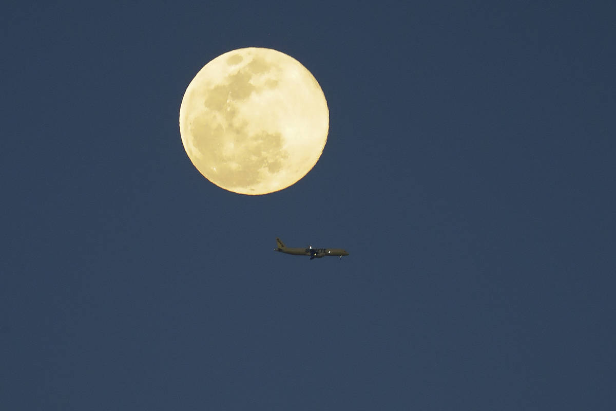 Un avión pasa por delante de la superluna mientras se eleva en el cielo el martes, 7 de abril ...