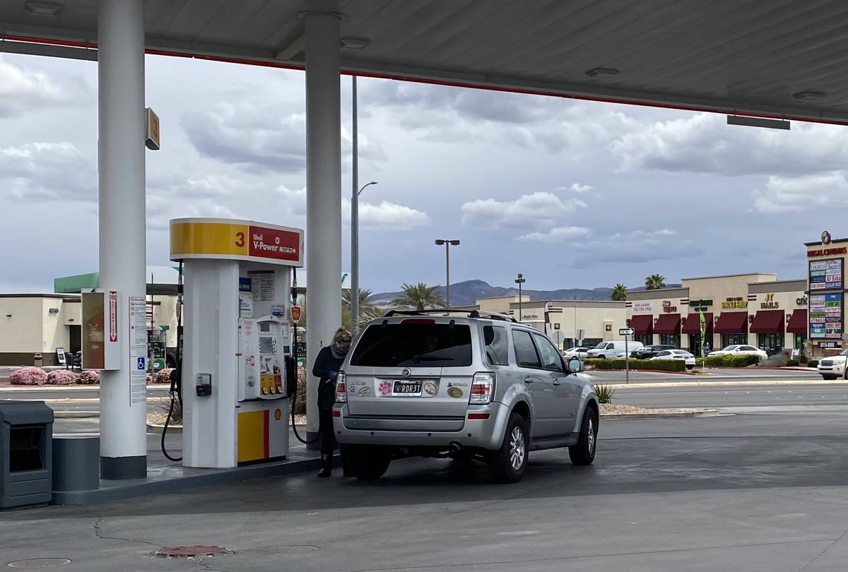 Una mujer con un cubrebocas de los Raiders llena su tanque de gasolina en la estación Shell en ...