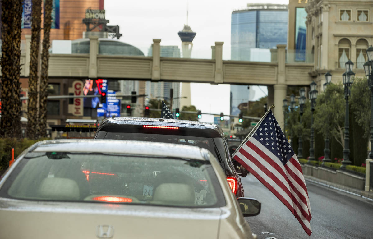 Algunos participantes ondean banderas estadounidenses mientras los vehículos suben por el Stri ...