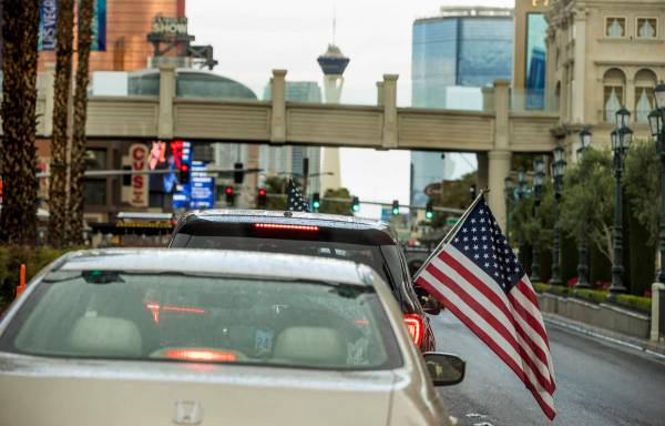 Algunos participantes ondean banderas estadounidenses mientras los vehículos suben por el Stri ...