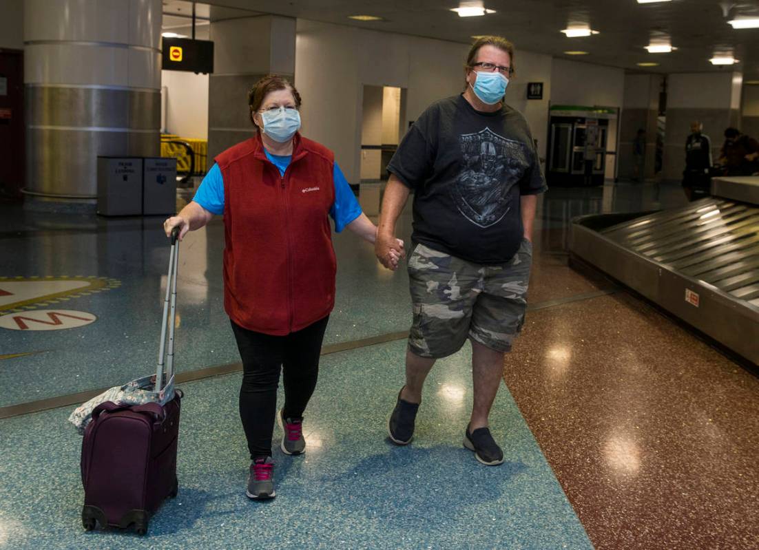 Susan Yowell y su marido Jack se toman de la mano al salir de la Terminal 1 de reclamo de equip ...