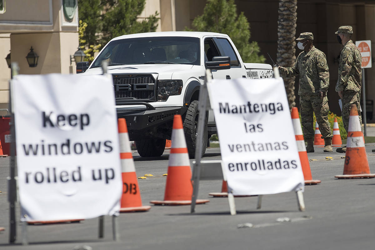 Miembros de la Guardia Nacional de Nevada dirigen a una persona en la estación de pruebas driv ...