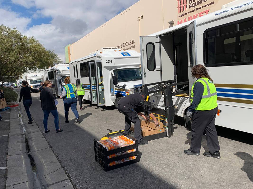 Trabajadores (y voluntarios de Three Square Foiod Bank) cargan víveres en vehículos de paratr ...