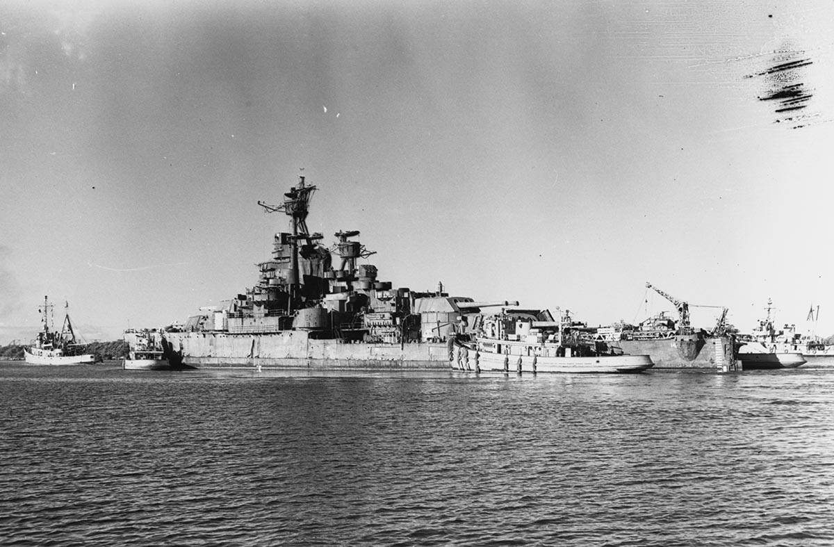La salida del USS Nevada de Pearl Harbor remolcado por el USS Jicarilla el 26 de julio de 1948. ...
