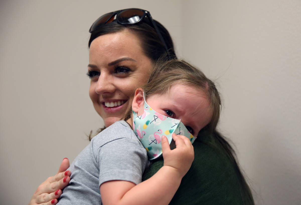 Olivia Hippert, de dos años, es consolada por su madre Amanda después de recibir su vacuna co ...