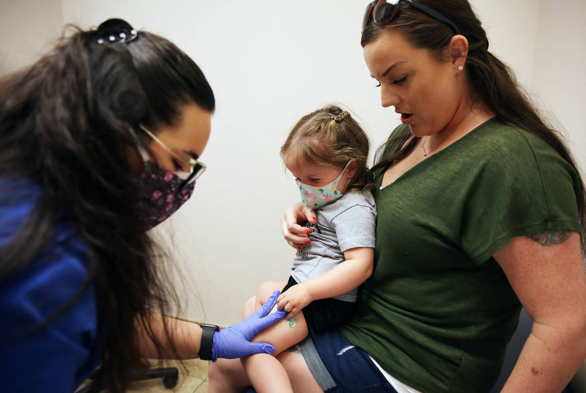 Olivia Hippert, de dos años, es consolada por su madre Amanda después de recibir su vacuna co ...