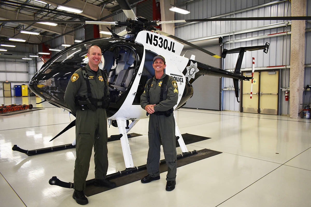 El oficial Ryan Petersen (izquierda) y el sargento Spencer Basner posan frente a un helicópter ...
