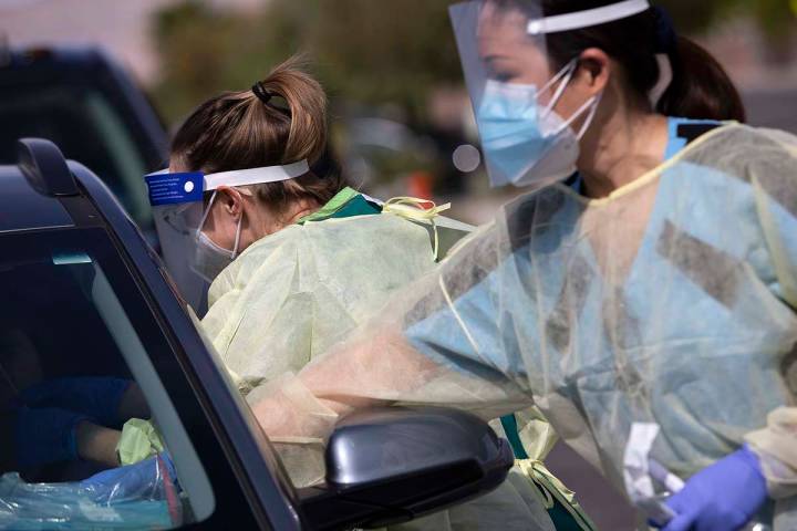 Una voluntaria toma la muestra de la nariz de un paciente en un sitio de pruebas de COVID-19 en ...