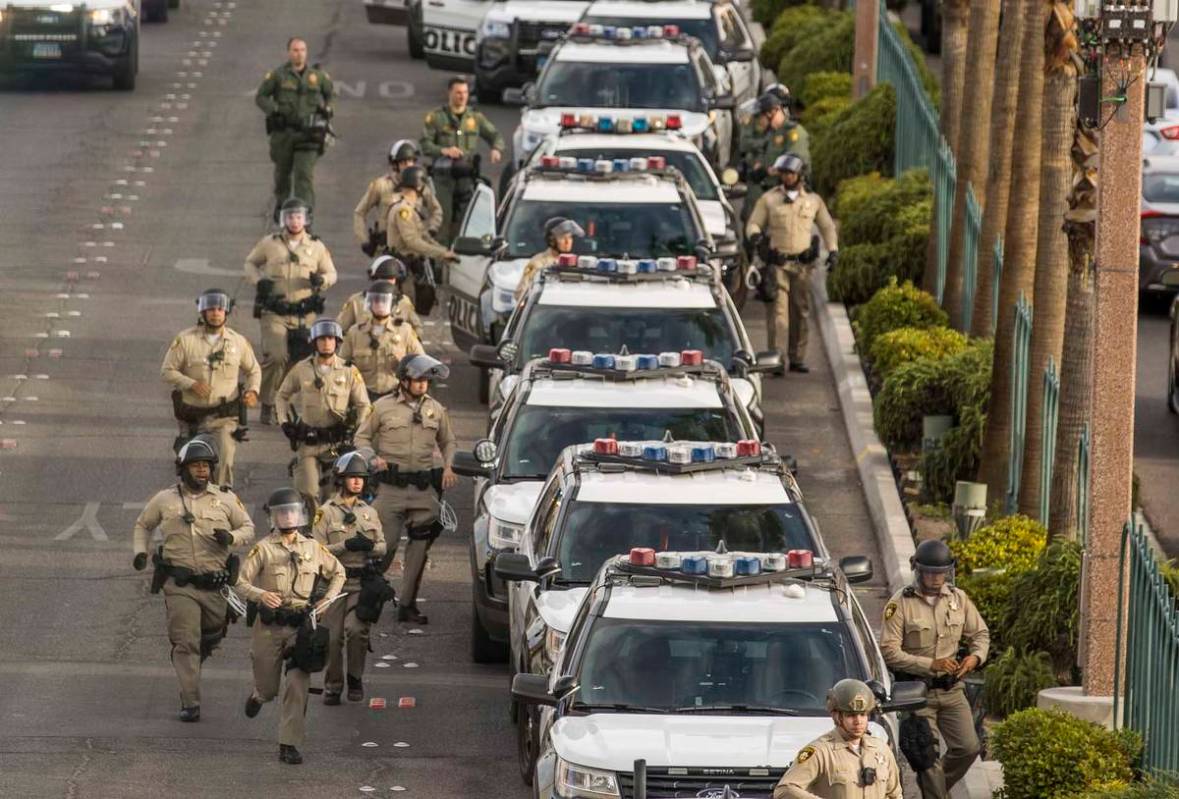 Oficiales de policía de Las Vegas corren a sus vehículos durante una protesta de Black Lives ...