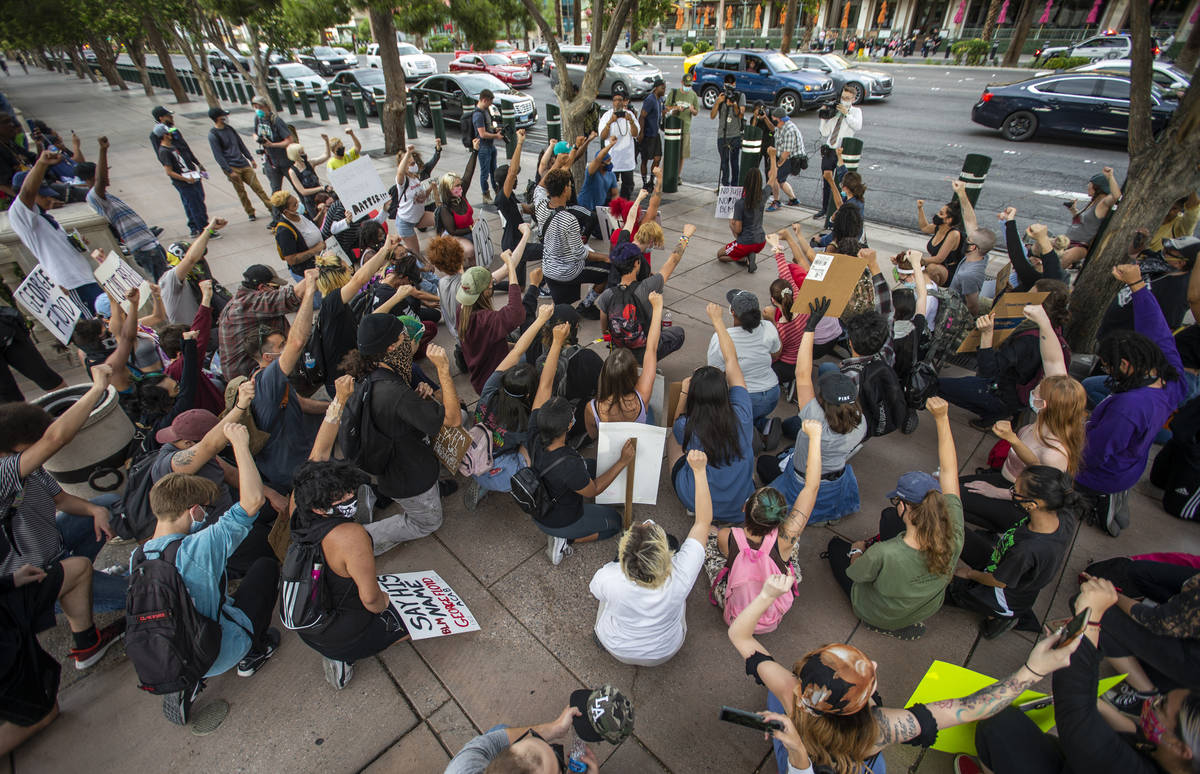 Manifestantes se arrodillan y levantan los puños en unidad fuera del Bellagio durante una prot ...
