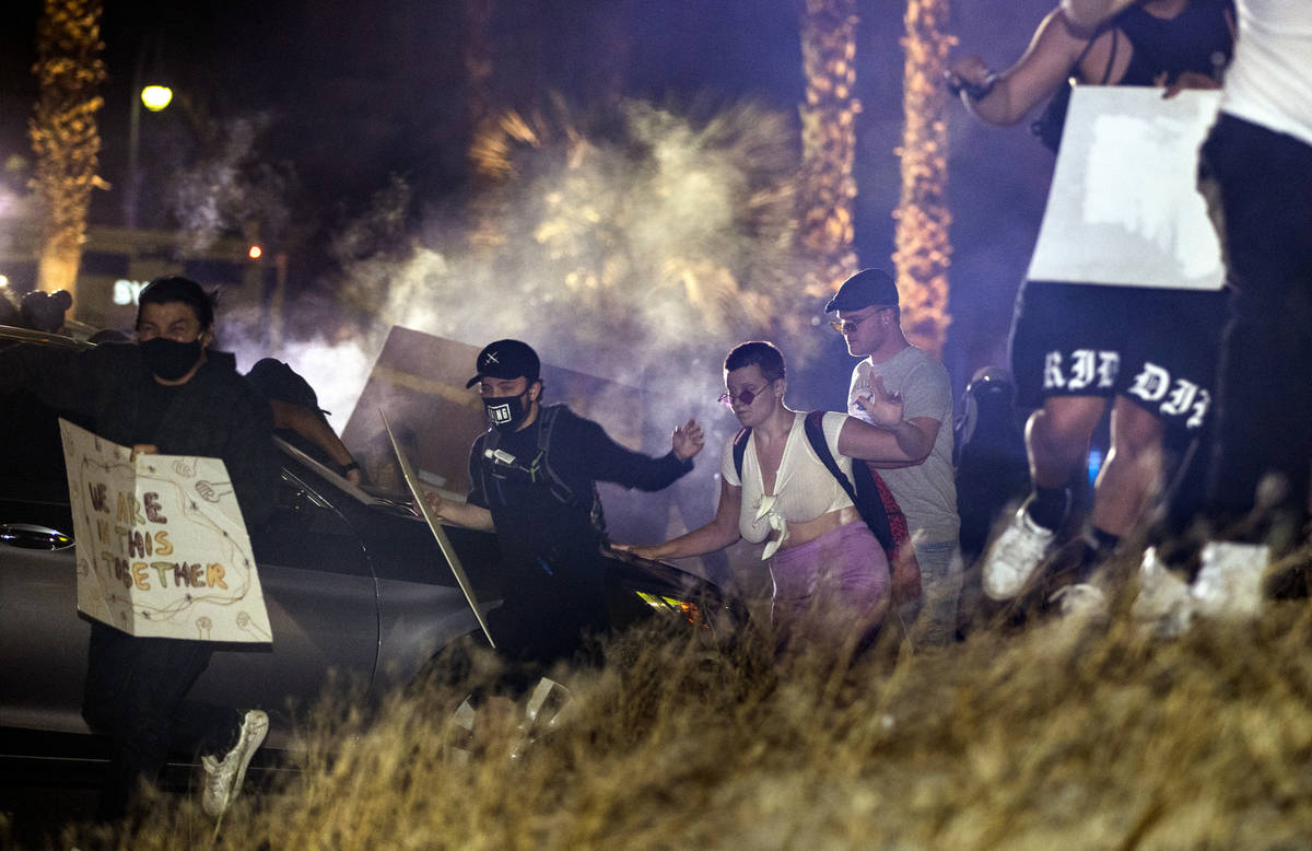 Manifestantes corren después de que la policía de Las Vegas disparara gas lacrimógeno y bala ...