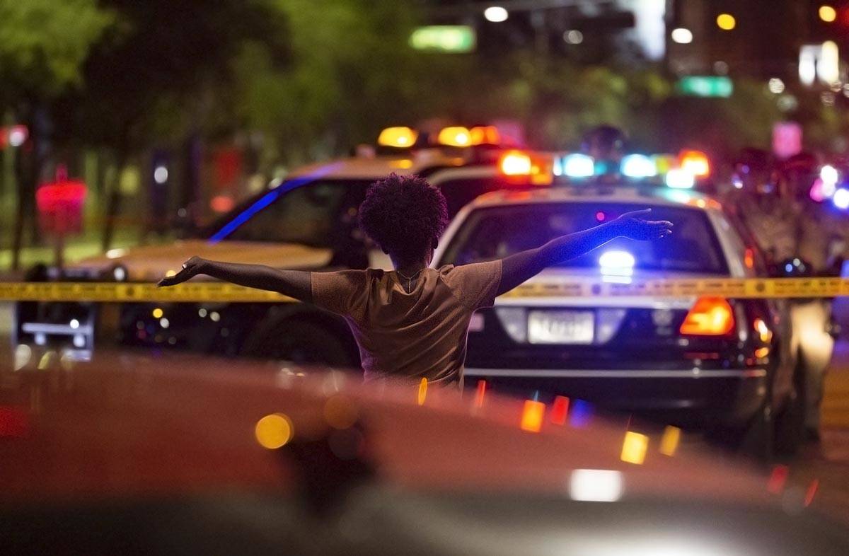 Una mujer camina hacia la policía con las manos en alto después de saber que un manifestante ...