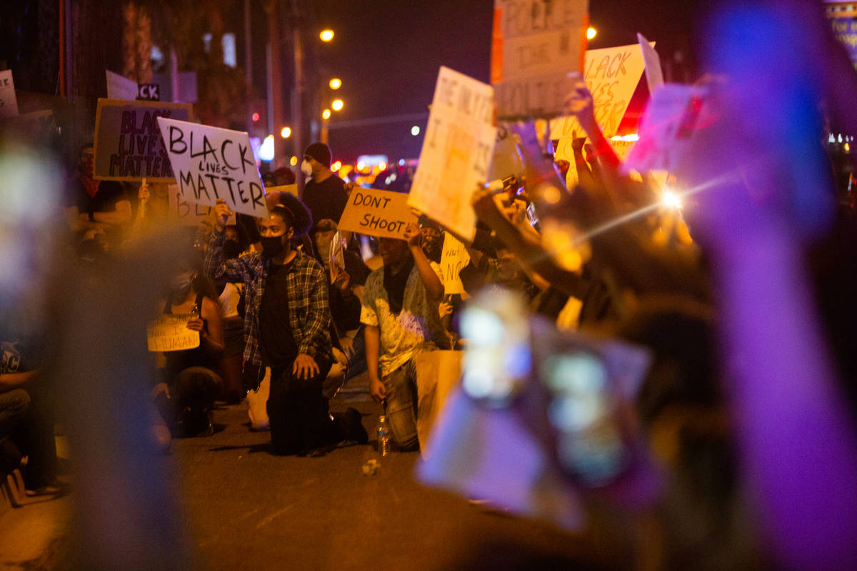 Manifestantes se arrodillan juntos antes de hacer un momento de silencio durante una protesta d ...