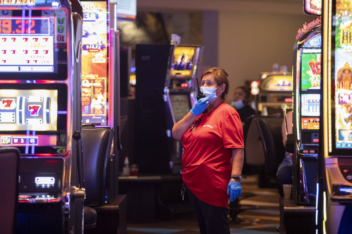 Empleados usan cubrebocas y guantes mientras limpian el piso del casino en Palace Station el do ...