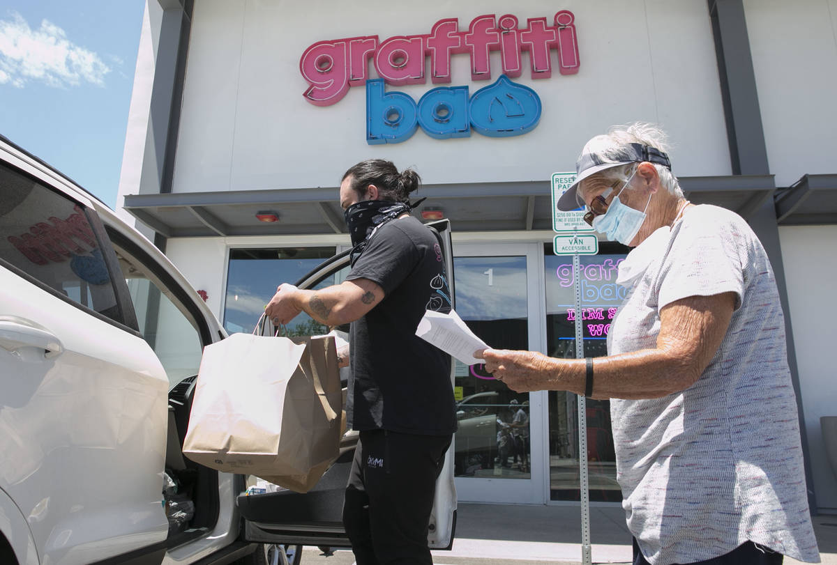 Marc Marrone, chef y propietario de Graffiti Bao, lleva bolsas de comida a la voluntaria, Cecil ...