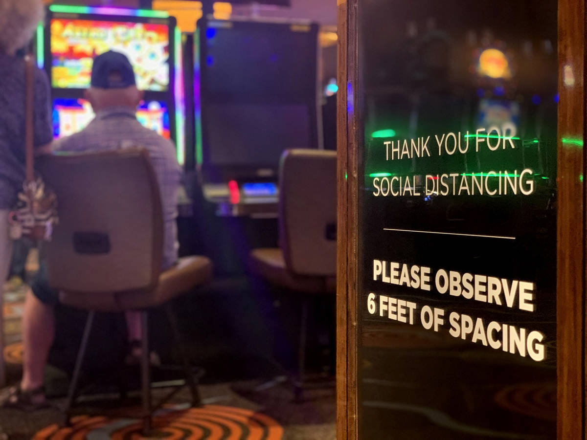 Un letrero que pide distanciamiento social se ve mientras los individuos juegan en el Casino Gi ...