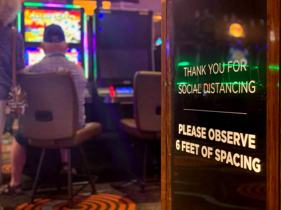 Un letrero que pide distanciamiento social se ve mientras los individuos juegan en el Casino Gi ...