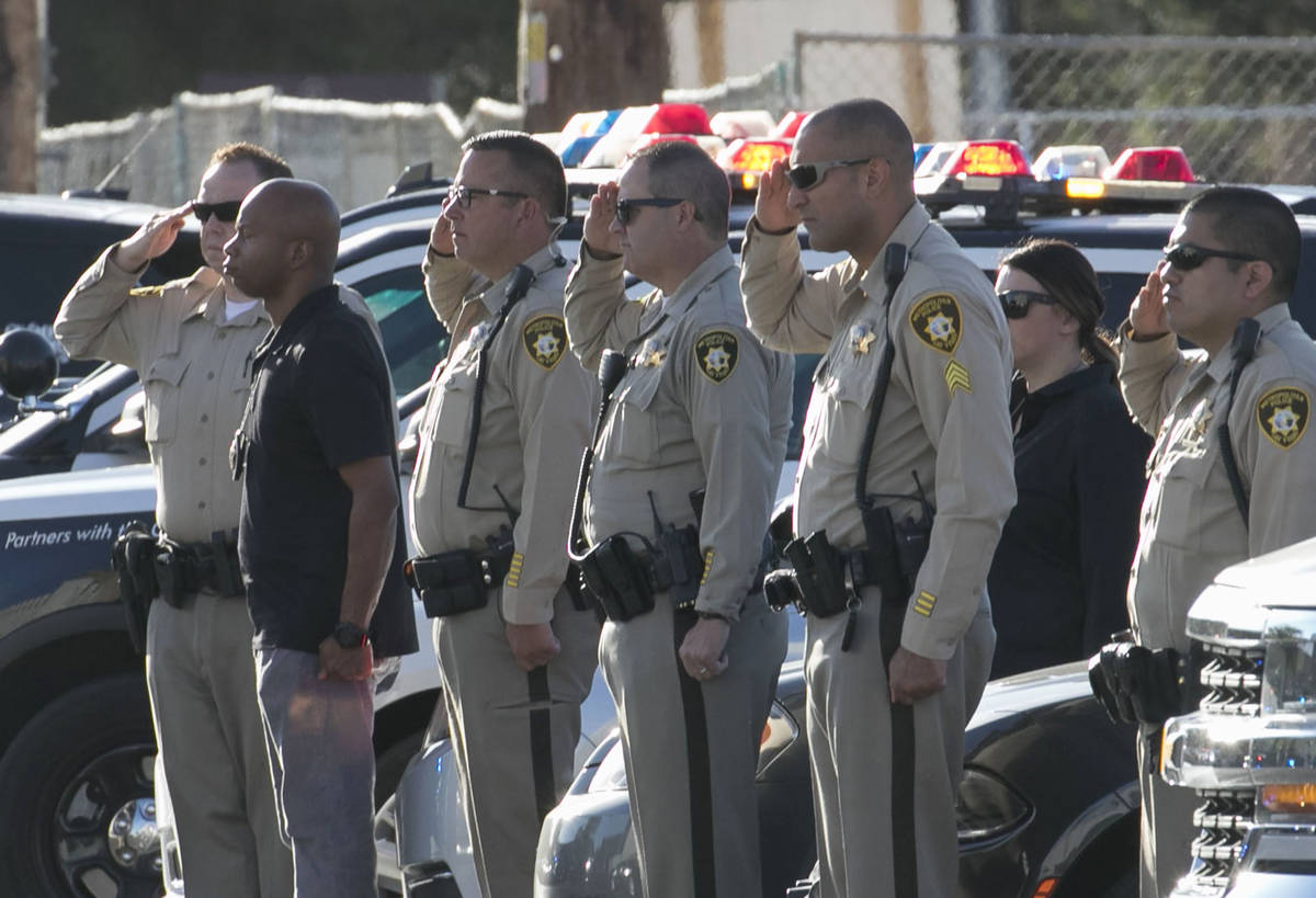 Oficiales de policía de Las Vegas saludan durante una procesión en la que una ambulancia que ...