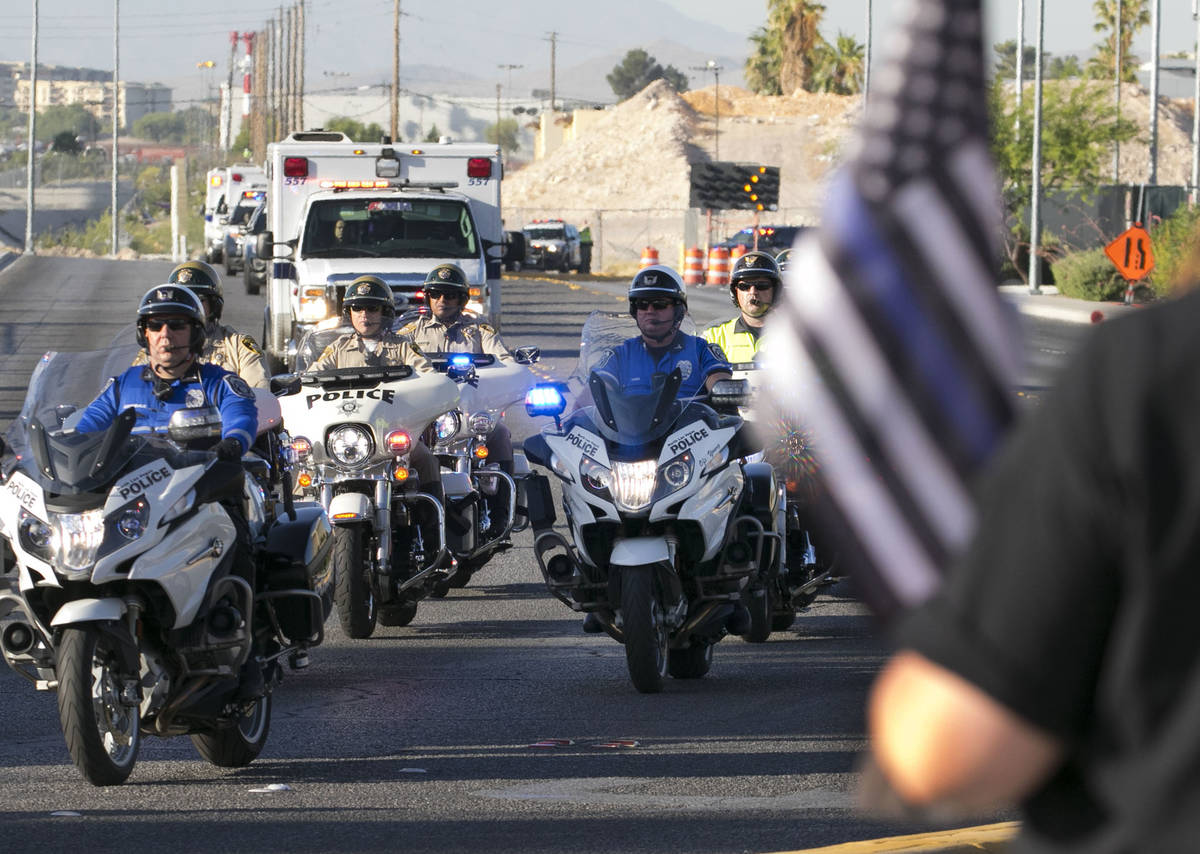 Cindy Novak, derecha, observa una procesión mientras una ambulancia que lleva al oficial de po ...