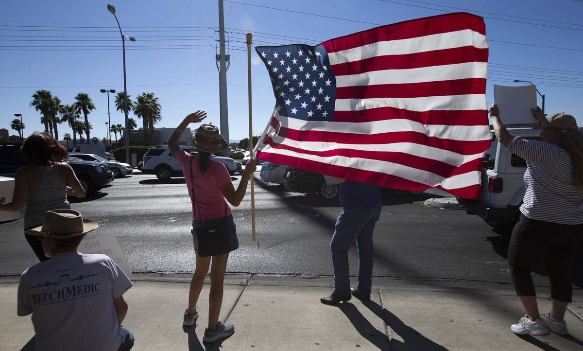 Faith Muello, segunda a la izquierda, sostiene una bandera estadounidense en la “No Mask Prot ...
