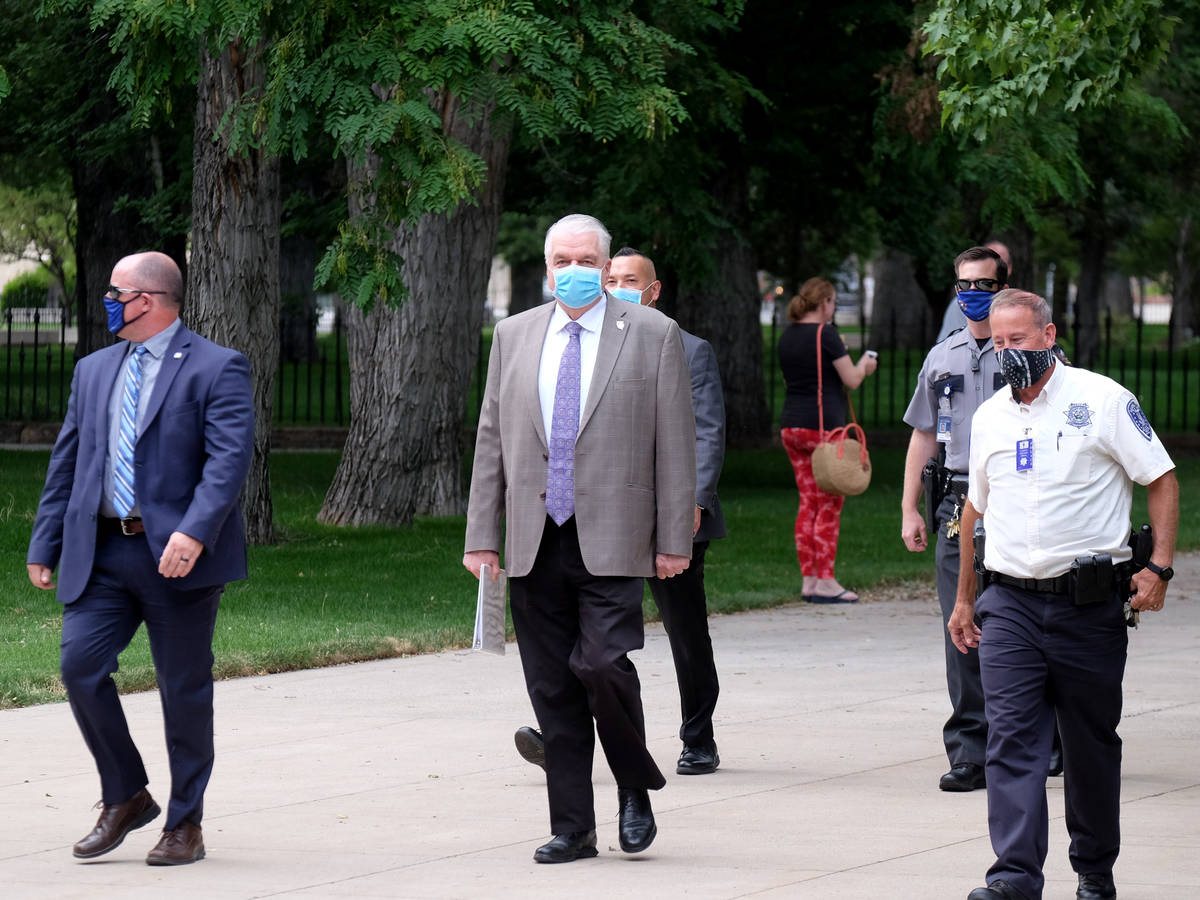 El gobernador Steve Sisolak camina hacia reunión informativa el lunes donde anunció que los b ...